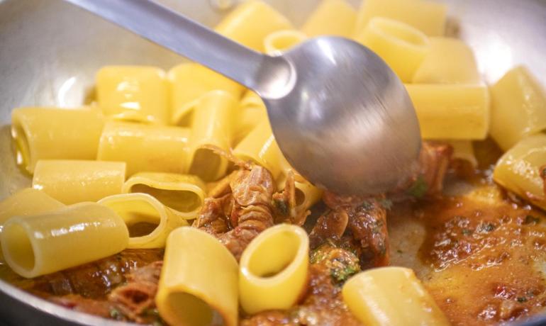 Heiße Rigatoni-Nudeln in einer Pfanne mit würziger Sauce gerührt.